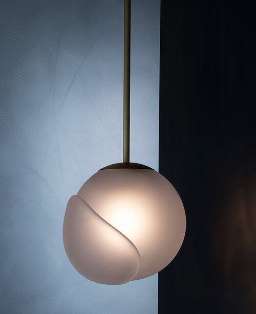 Round pendant with overlapping slab of glass.