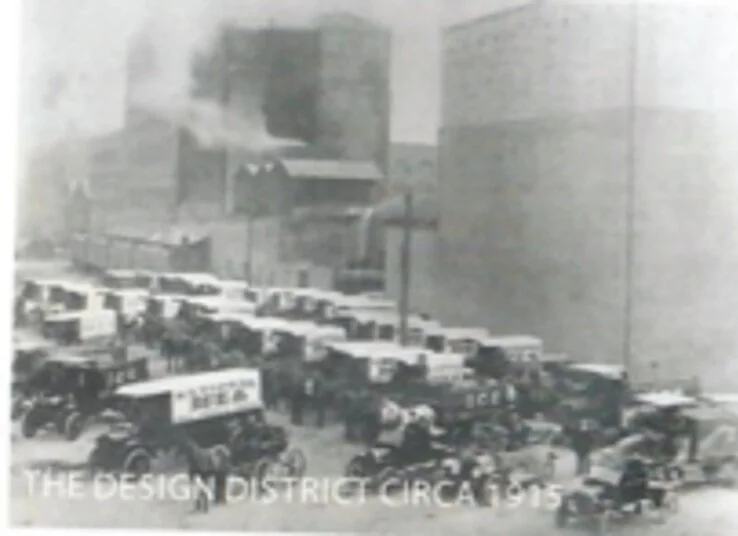 Slightly blurry black and white image with delivery trucks and horse-drawn wagons. The words "The Design District Circa 1915" at bottom left.