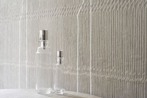 Vertical woven textured wallcovering behind counter with two clear bottles.
