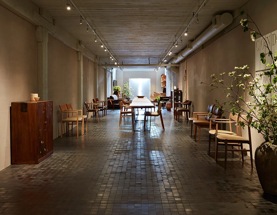 Large tunnel like concrete hall dressed with long wooden conference table and lined with chairs.