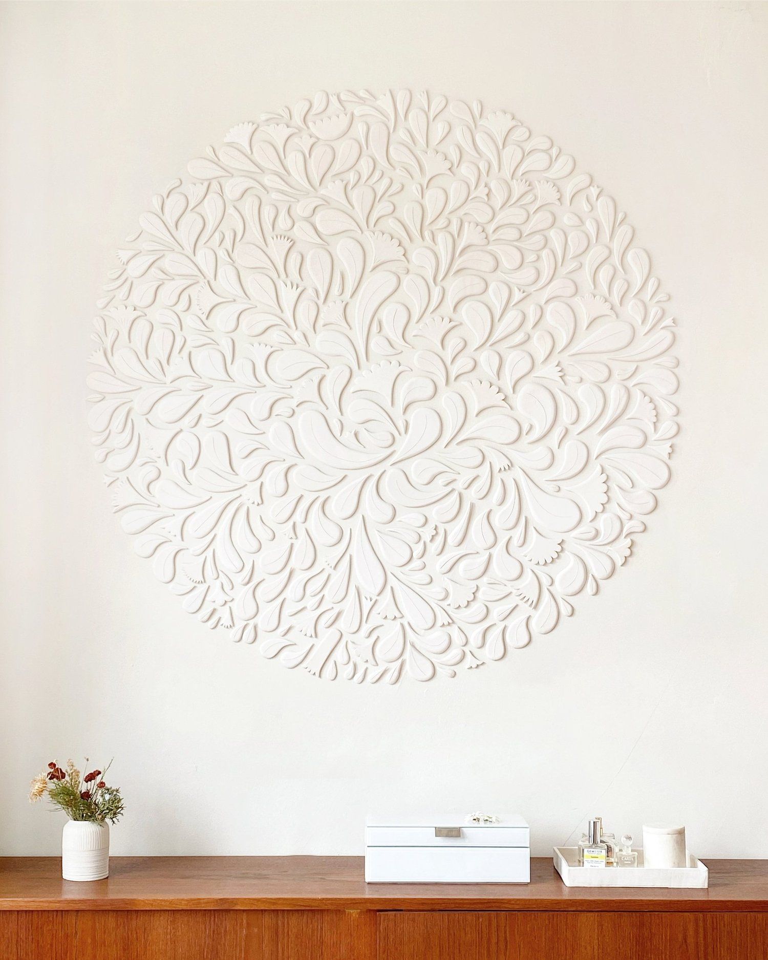 Circular ceramic emblem on wall over a credenza.