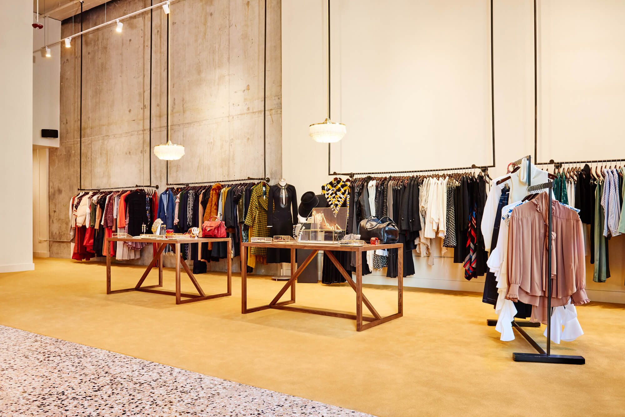 Large open, high-ceilinged, well-lit industrial shop with clothes hung from pipes.