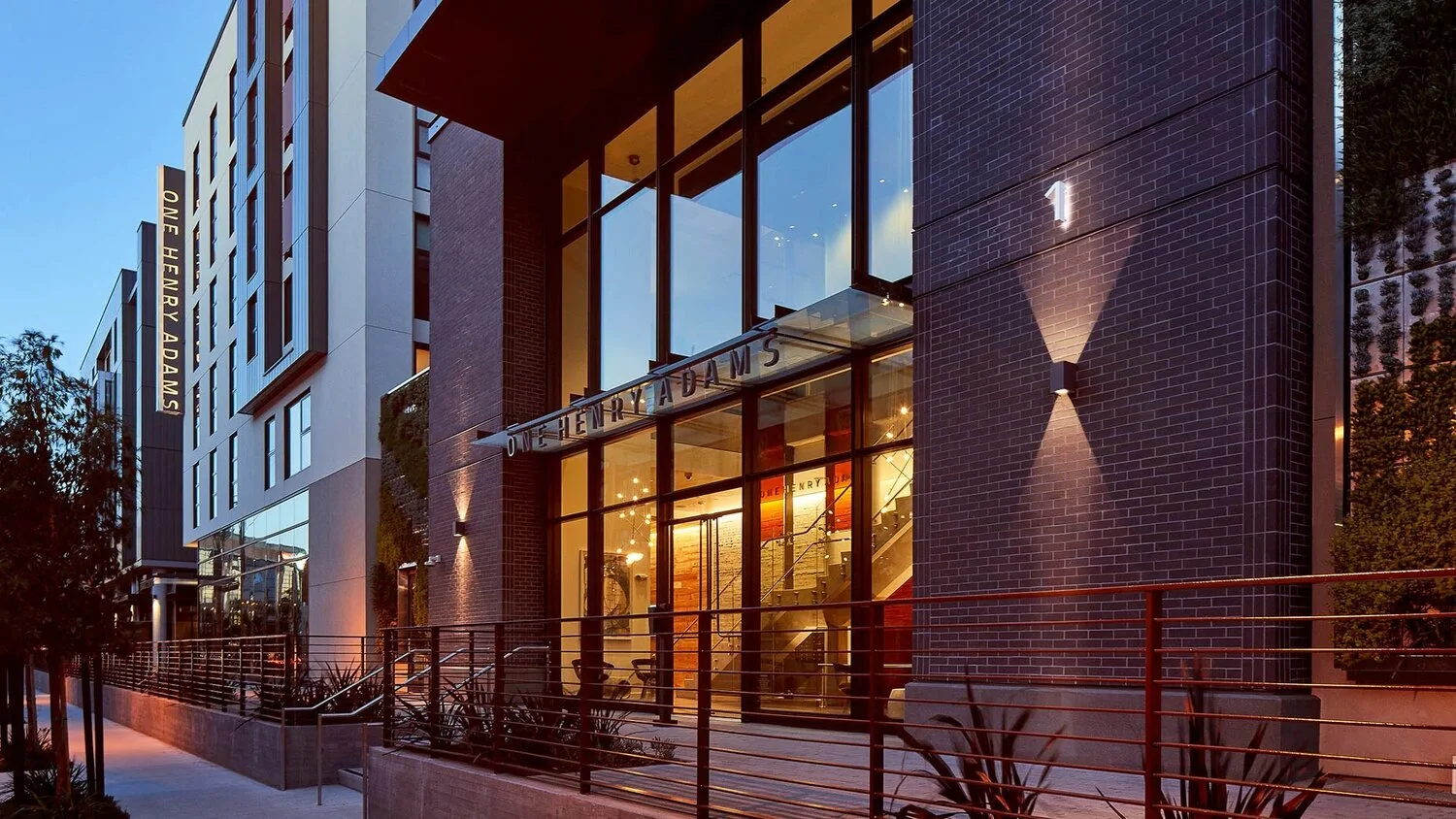 Upscale modern building facade with sign visible "One Henry Adams".