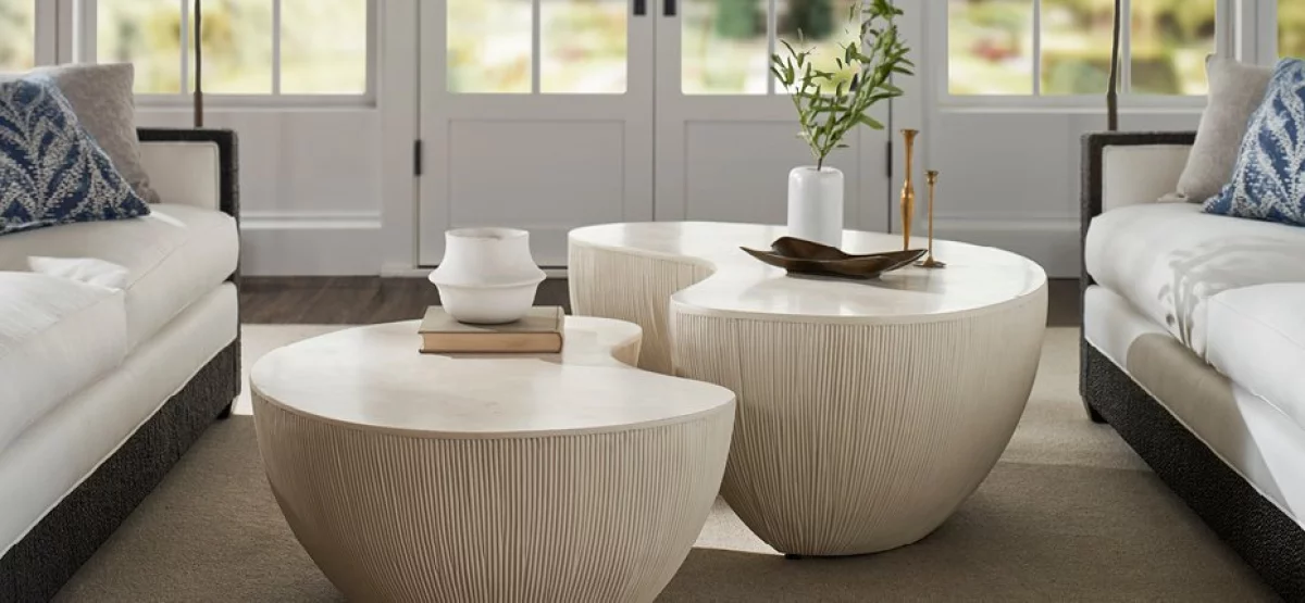 Upscale modern living room in light tones with two bean shaped stone coffee tables center.