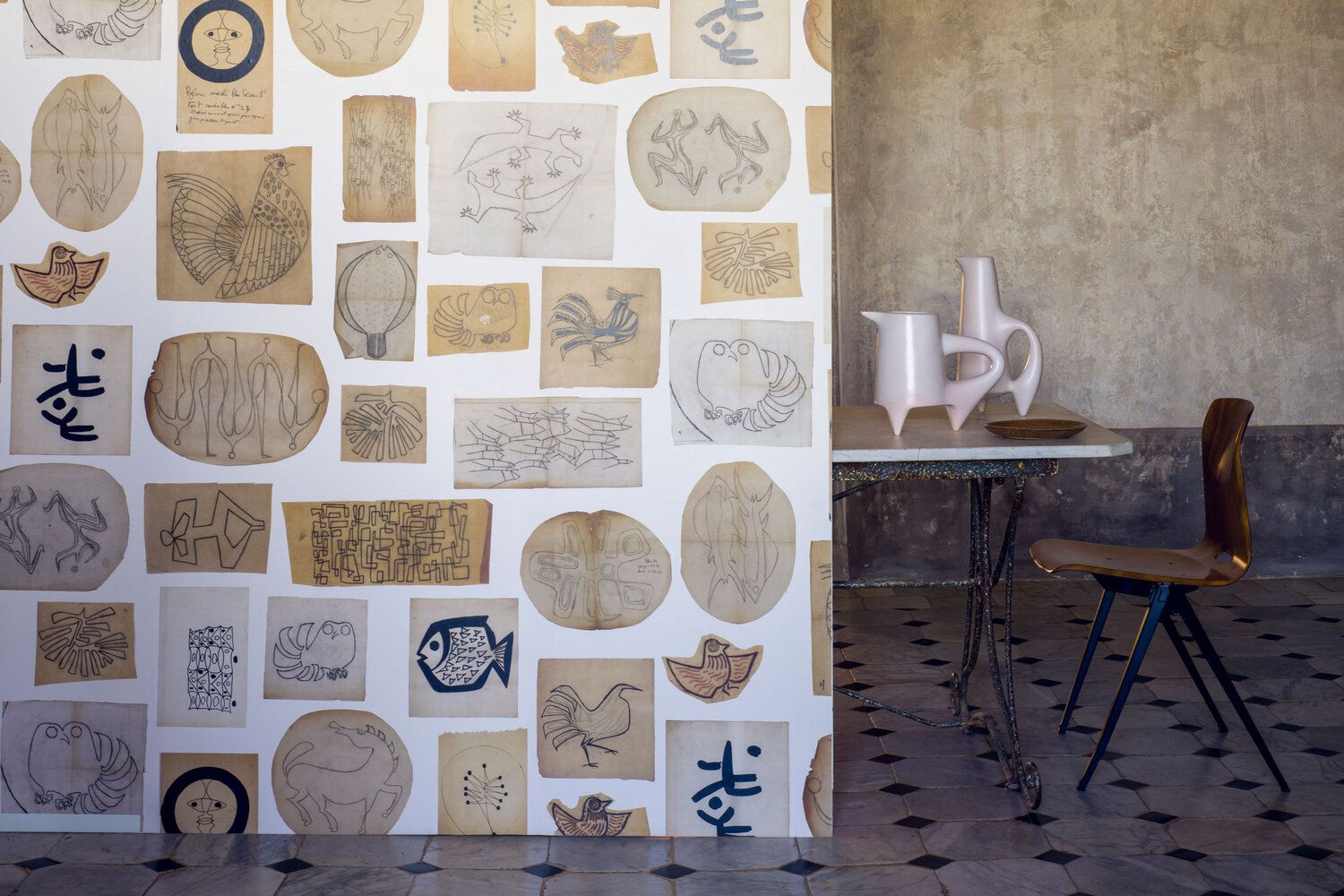 Wallcovering that looks like it is covered in cutouts of drawings hung on a wall in a kitchen.