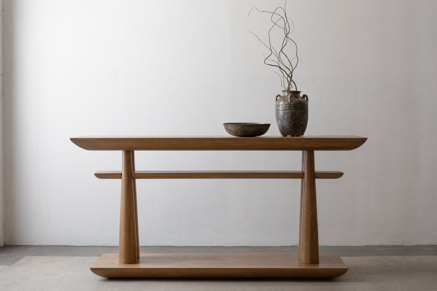 Rectangular modern couch table with ceramic bowl and jar with willow branches in it.