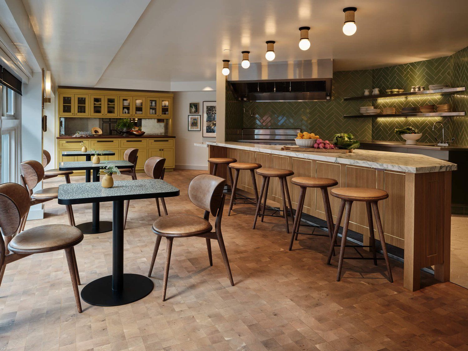 Modern open kitchen with counter seating, small tables and chairs and built in cabinetry.