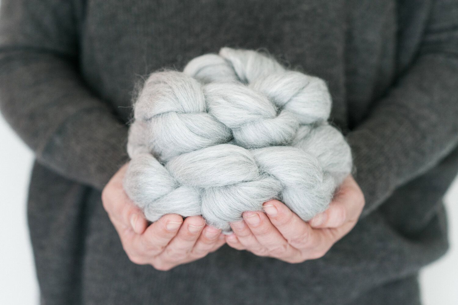 Closeup of someone's hands holding a braided coil of yarn.