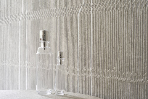 Vertical woven textured wallcovering behind counter with two clear bottles.