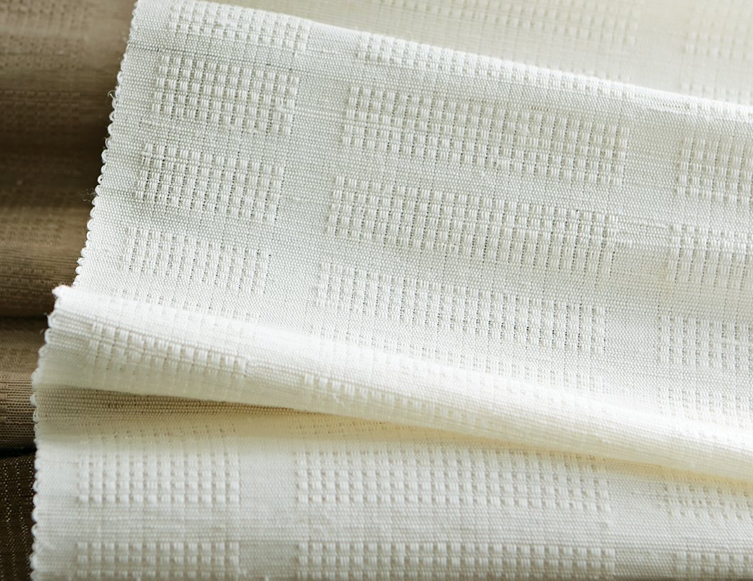 Three images: Closeup of woven fabric with square bumpy weave. Closeup of fabric with semi sheer effect of light color grasscloth pattern. The grasscloth pattern in a roman shade on a window with chair and table in front.