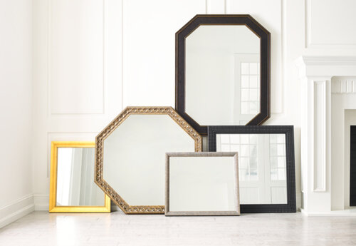 A variety of wood framed wall mirrors leaning against a wall.