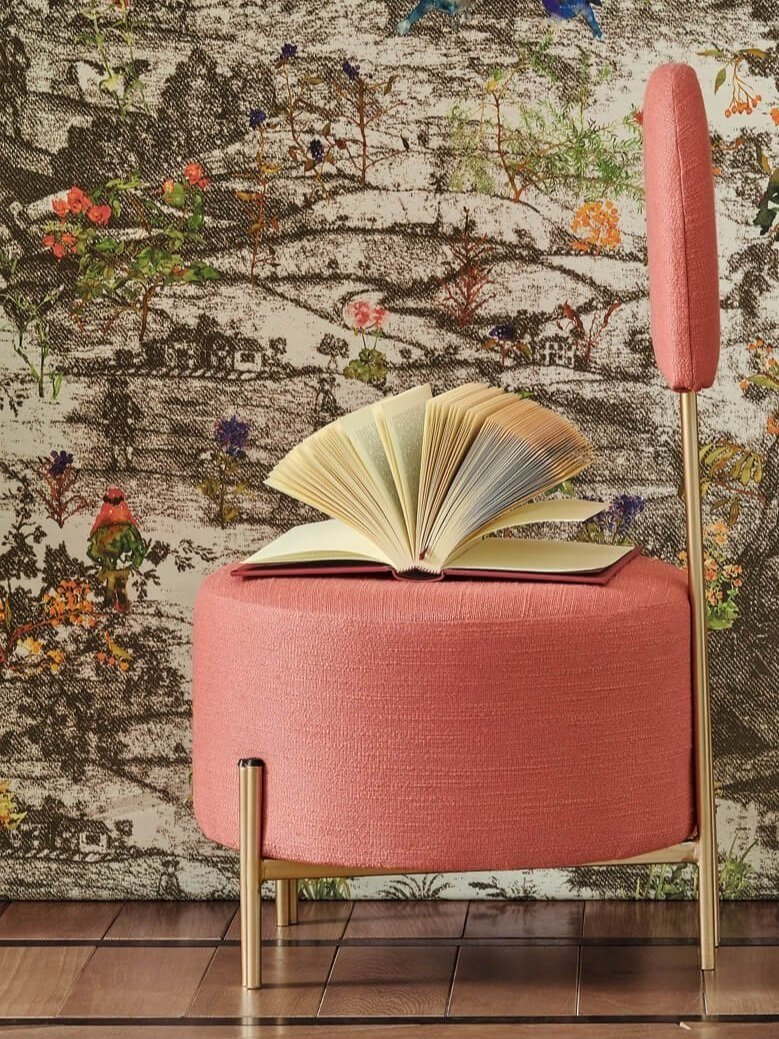 Stylized garden wallcovering on wall behind stylish chair with an open book on seat.