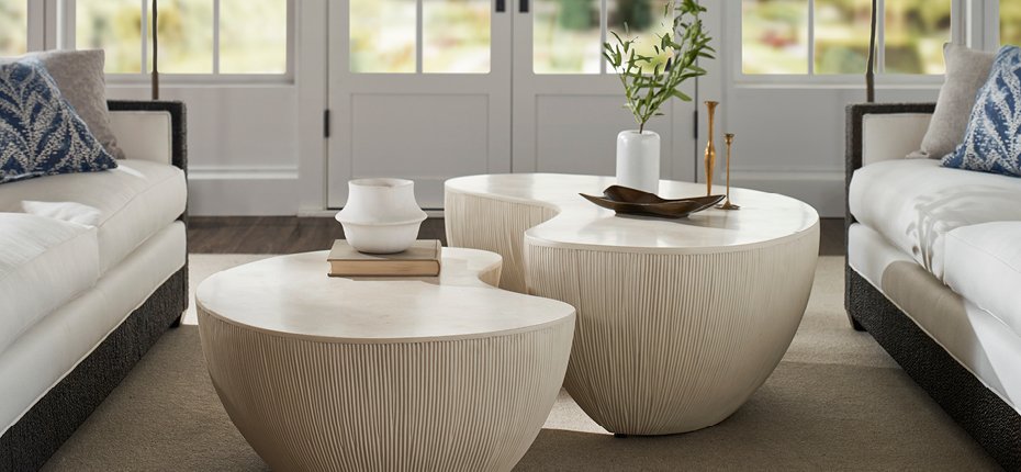 Upscale modern living room in light tones with two bean shaped stone coffee tables center.