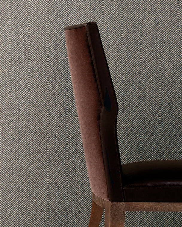 Upholstered dining chair in front of a herringbone patterned wallcovering.