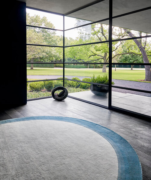 Round rug in a glass walled room.