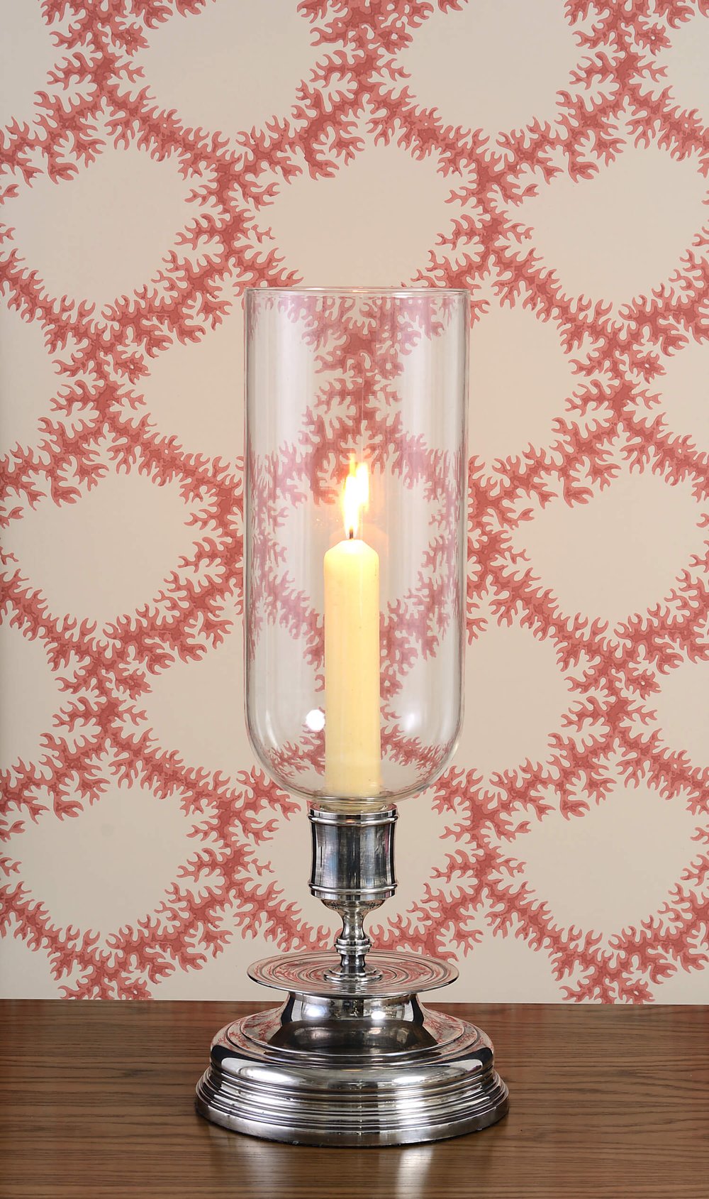 Woven vine wallcovering behind lit hurricane style candlestick.