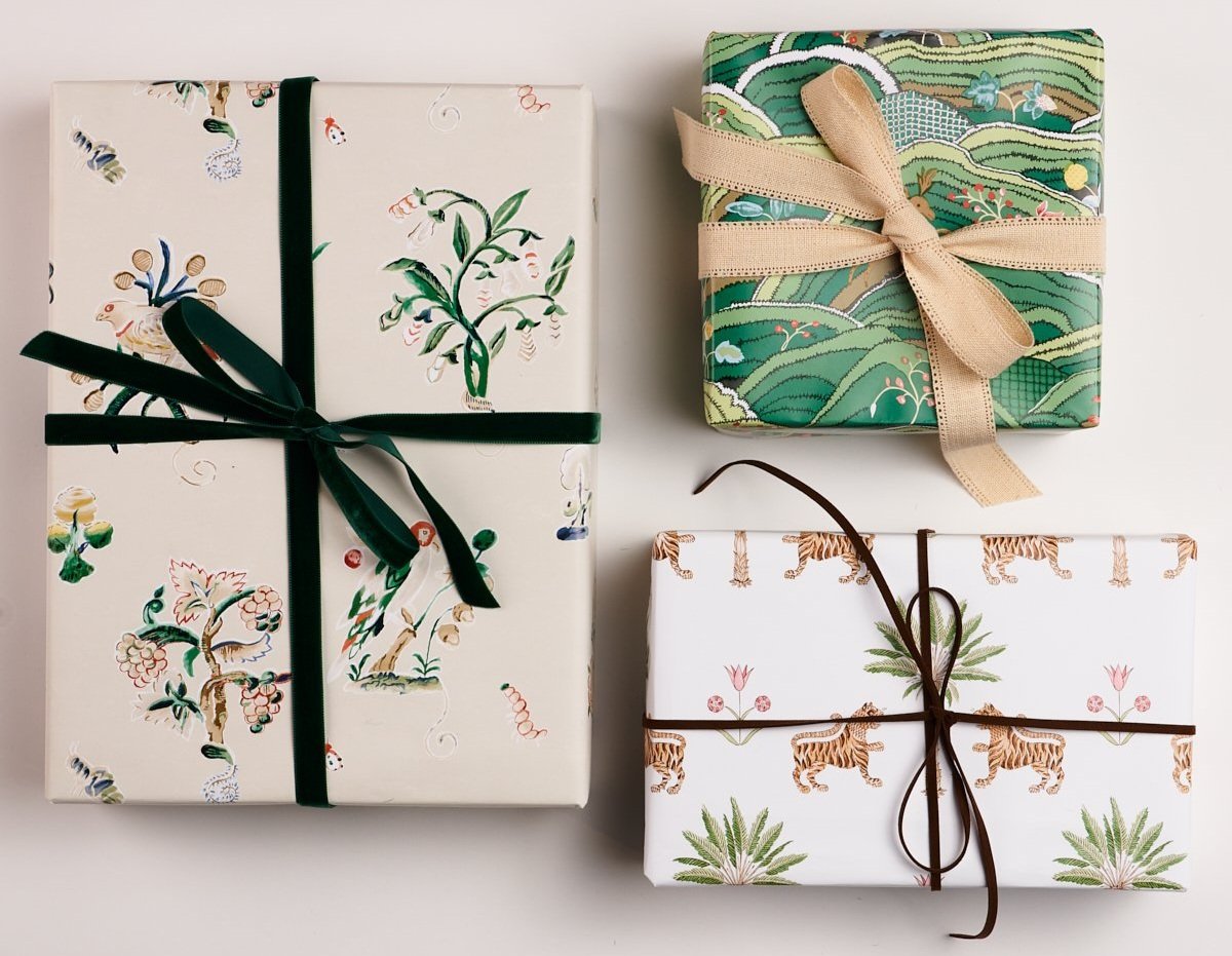 Three beautifully wrapped packages with nature themed paper and solid color ribbons.
