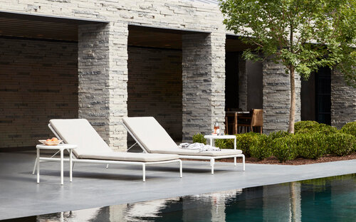 Two simple lounge chairs with side tables by pool.