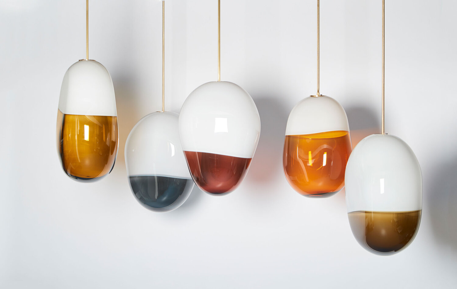 Collection of two toned, multi-shaped and colored blown glass pendulum lights.