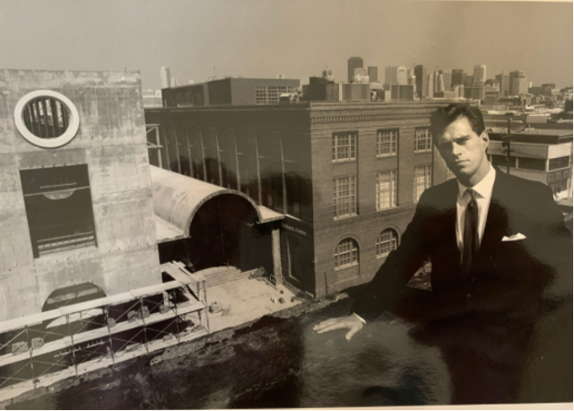 Young man in suit on roof overlooking a construction site.